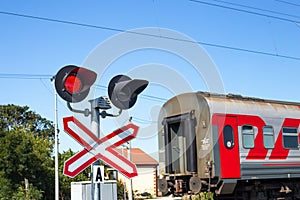 The outgoing train travels through the level crossing with the traffic light on. Convenient fast transportation