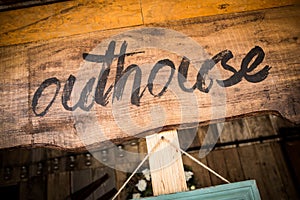 Outhouse sign on wooden board