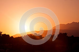 Outline photo of sun setting over mountains