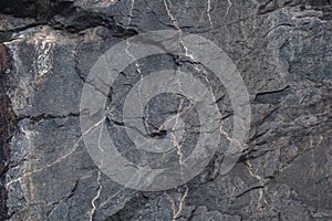 The output of dark shale rock with veins, natural stone background.