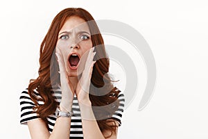 Outraged angry young redhead woman in striped t-shirt accuse someone, cup hands around opened mouth, cursing bad person