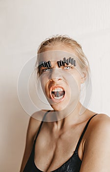 Outraged evil screaming girl with pill eyebrows and a capsule in the mouth. Closeup portrait