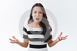 Outraged, pissed angry asian woman in striped t-shirt, have huge complain look annoyed and bothered, frowning, hands