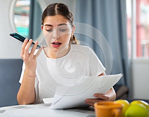 Outraged woman with documents in her hands talking on mobile phone