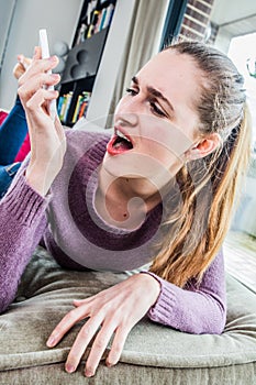 Outraged young woman looking at her mobile phone with irritation