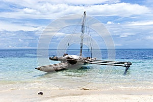 Outrigger canoe on sandy beach in lagoon