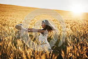 Outside is her favourite place to be. Shot of a cute little girl playing with her teddybear in a cornfield.