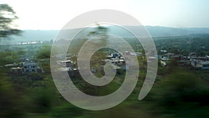 Outside valley and distant cityscape view through the window of a moving train while traveling to Mata Vaishno Devi Shrine. Katra