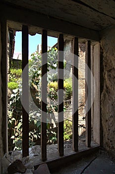 An outside view from a window secured with iron bars revealing rural India.