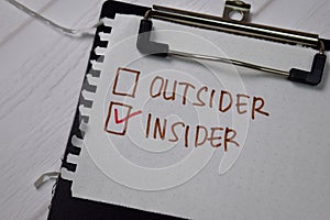 Outsider and Insider write on a sticky note. Supported by an additional services isolated wooden table