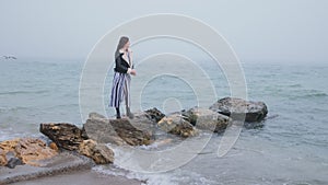 Outsider. Sad, depressed young woman on beach near sea alone looking on storm