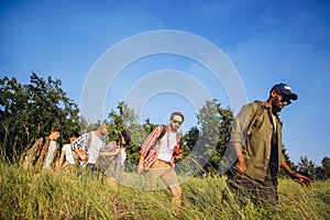 At outskirts of city. Group of friends, young men and women walking, strolling together during picnic in summer forest