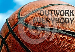 Outwork everybody written on an orange basketball