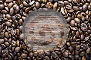 Oval of coffee beans on a wooden fone