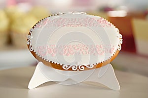 An oval cookie,decorated with glazed pattern on the white stand