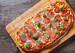 Oval Pizza with Mozzarella cheese, Tomatoes, pepper, Spices and Fresh Basil. Italian pizza. Pizza Margherita or Margarita on woode