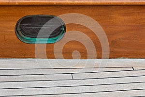 Oval ships porthole window by the deck of a sailboat, screen and verdigris patina, creative copy space photo