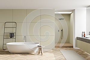 Oval white bathtub in light olive bathroom space