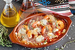 Oven backed prawns with feta, tomato, paprika, thyme in a traditional ceramic form on a abstract background. Healthy eating concep