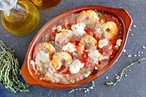 Oven backed prawns with feta, tomato, paprika, thyme in a traditional ceramic form on a abstract background. Healthy eating concep