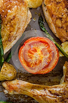 Oven-baked chicken with vegetables on the roasting tray