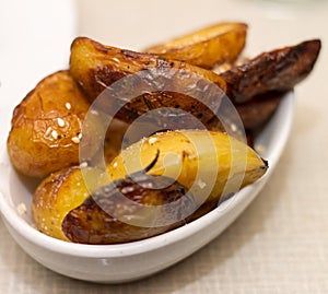 Oven baked potatoes in white bowl on beige