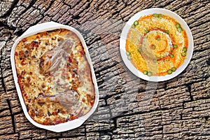 Oven Baked Vegetable Stew With Chicken Meat And Bowl Of Garnished Russian Salad Set On Old Stump Weathered Cracked Top Surface photo
