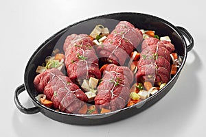 Oven dish with raw beef roulades and vegetables