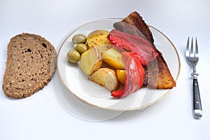 oven grilled bacon slices with delicious curry sauce served on white plate, baked potatoes with meat, red paprika, green capsicum