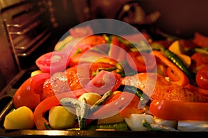 oven grilled chicken legs with delicious curry sauce served on baking tray, baked potatoes with meat, red paprika, green capsicum