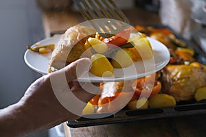 oven grilled chicken legs with delicious curry sauce served on white plate, baked potatoes with meat, red paprika, green capsicum