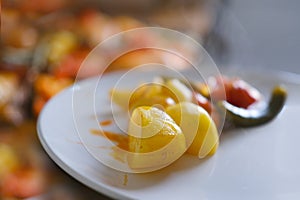 oven grilled chicken legs with delicious curry sauce served on white plate, baked potatoes with meat, red paprika, green capsicum