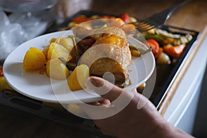 oven grilled chicken legs with delicious curry sauce served on white plate, baked potatoes with meat, red paprika, green capsicum