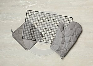 Oven mitt, potholder and cooling rack on grey table, flat lay. Cooking utensils