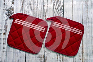 Oven potholders for hot dishes on wooden background, top view