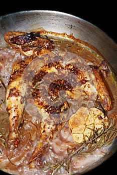 Oven roasted baby chicken with onions and galic in a pan, dish known as spatchcock