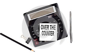 OVER THE COUNTER text on sticker on calculator with pen,pencil on the white background