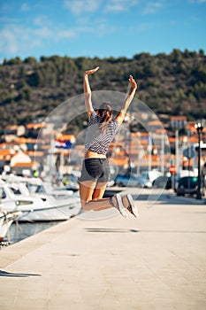 Over exited happy woman jumping in the air out of happiness. Vacation time concept. Seaside coastal vacation excitement. Woman in