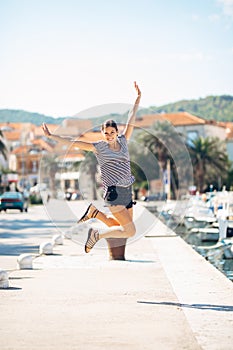 Over exited happy woman jumping in the air out of happiness. Vacation time concept. Seaside coastal vacation excitement. Woman in