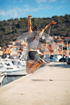 Over exited happy woman jumping in the air out of happiness.Vacation time concept.Seaside coastal vacation excitement.Woman in joy