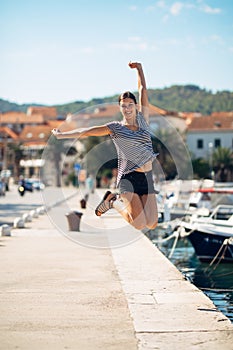 Over exited happy woman jumping in the air out of happiness.Vacation time concept.Seaside coastal vacation excitement.Woman in joy