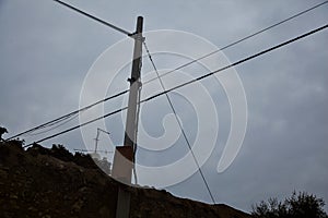 Over head cables held by pylons with a cloudy sky as background