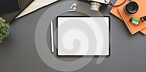 Over head shot of blank screen tablet on photographer table with other office supplies on grey background