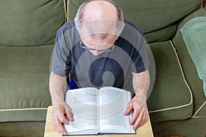 Over head view of balding man reading a book