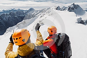 Over the head view, two mountaineers with helmets looking at the view of snowy Alps from high up