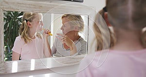 Over the shoulder view of Caucasian woman and her daughter brushing their teeth