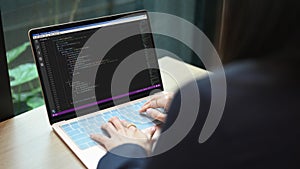 Over shoulder view of female software developer working on web site project, programming on desktop computer in startup