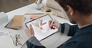 Over shoulder view of fmale artist drawing plant while creating illustration on tablet.Man graphic illustrator using
