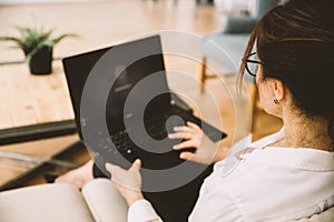 Over the shoulder view of middle-aged business woman working at home using laptop