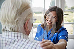 Over shoulder view of nurse on home visit with senior man